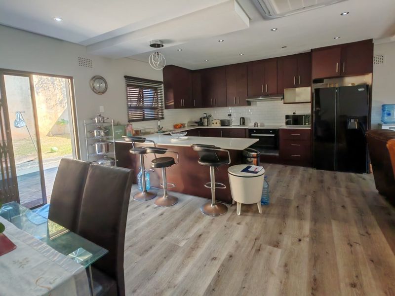 Spacious open-plan kitchen featuring dark wood cabinetry, stone countertops, a central island, and direct access to the outdoor patio area.