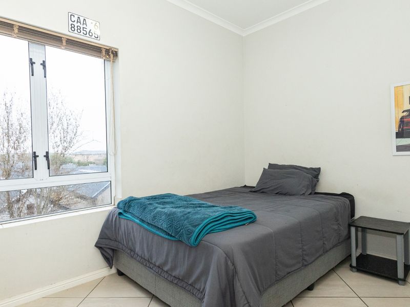 A bright bedroom featuring tiled flooring and a large window providing natural light and exterior views.