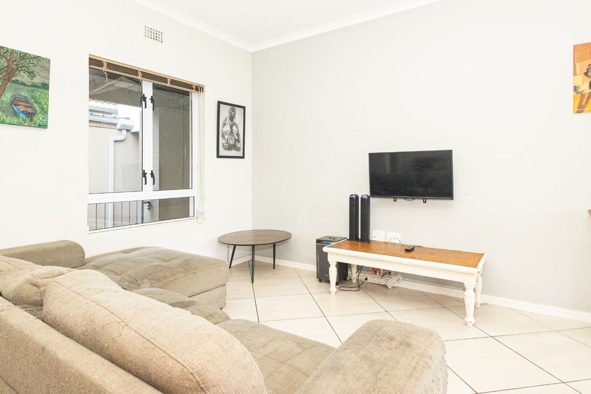 A bright living room featuring neutral tiled flooring, a large sliding window, and clean wall finishes, providing a comfortable and functional space.