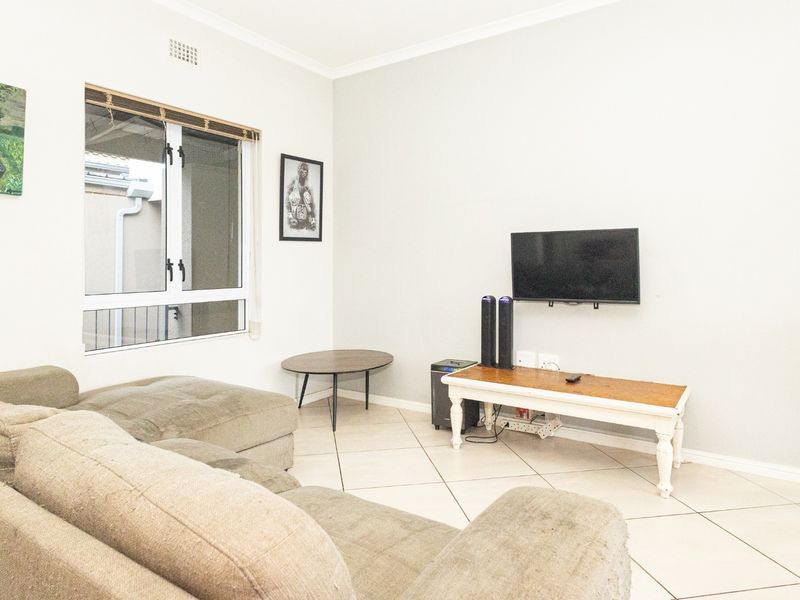 A bright living room featuring neutral tiled flooring, a large sliding window, and clean wall finishes, providing a comfortable and functional space.