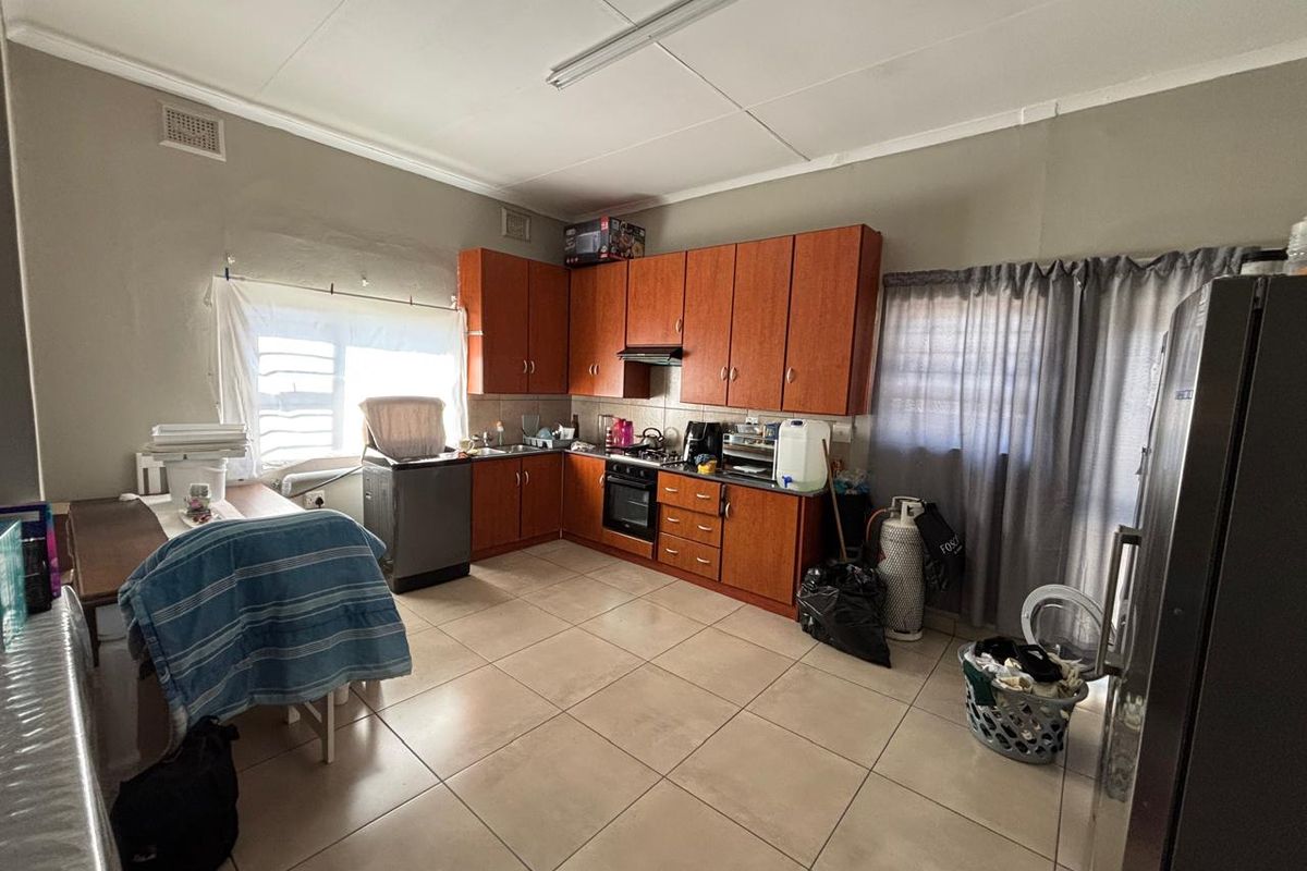 A functional kitchen featuring wooden cabinetry, built-in oven, gas hob, and tiled flooring, offering potential for modernization and aesthetic updates.