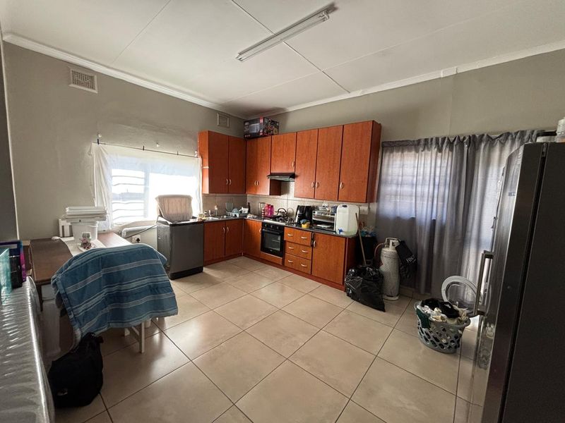 A functional kitchen featuring wooden cabinetry, built-in oven, gas hob, and tiled flooring, offering potential for modernization and aesthetic updates.