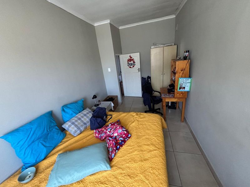 A standard bedroom featuring tiled flooring, a built-in cupboard, and neutral wall finishes.