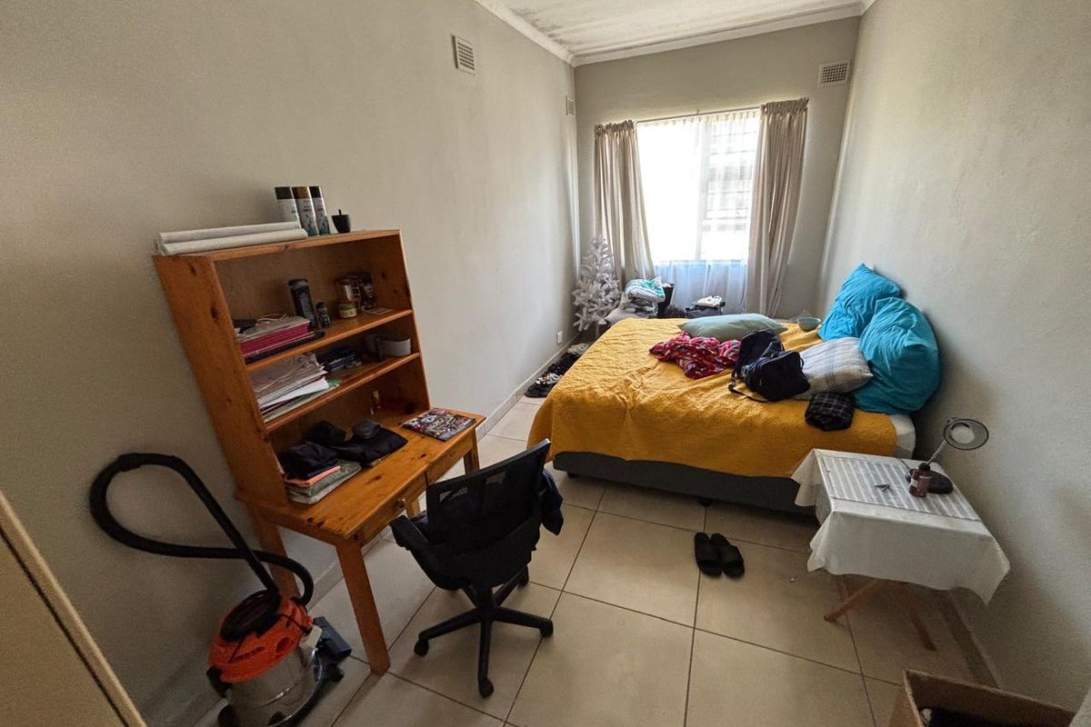 A bedroom featuring tiled flooring and visible ceiling water staining, offering a functional space ready for cosmetic updates.