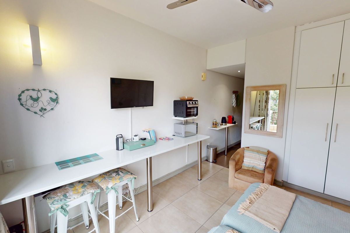 A functional bedroom featuring built-in cupboards, tiled flooring, and a ceiling fan, offering a practical layout with integrated storage solutions.