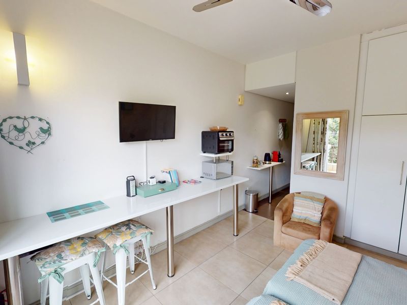A functional bedroom featuring built-in cupboards, tiled flooring, and a ceiling fan, offering a practical layout with integrated storage solutions.