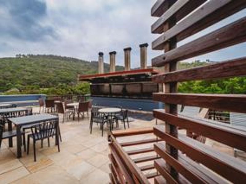 Spacious outdoor patio featuring a built-in braai area, stone tile flooring, and timber privacy screening with scenic hillside views.