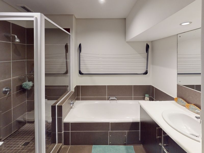 A modern bathroom featuring a glass-enclosed shower, a built-in bathtub with tiled surround, and a vanity unit with an integrated sink.