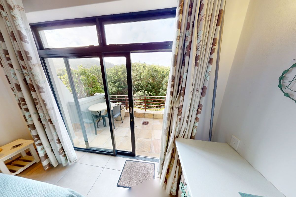 Bedroom featuring tiled flooring, a built-in desk, and large sliding glass doors providing direct access to a private balcony with scenic views.