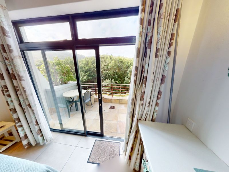 Bedroom featuring tiled flooring, a built-in desk, and large sliding glass doors providing direct access to a private balcony with scenic views.
