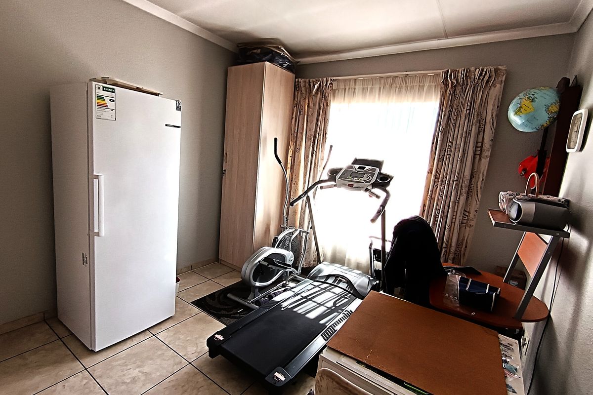 A functional bedroom space featuring tiled flooring and a built-in cupboard, currently utilized as a multi-purpose room.