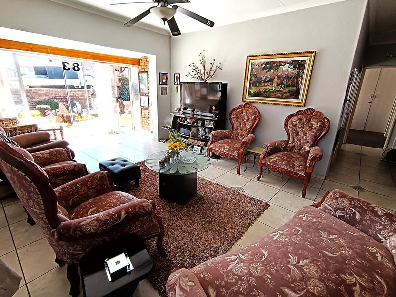 Spacious living room featuring tiled flooring, a ceiling fan, and large sliding glass doors providing access to the outdoor area.
