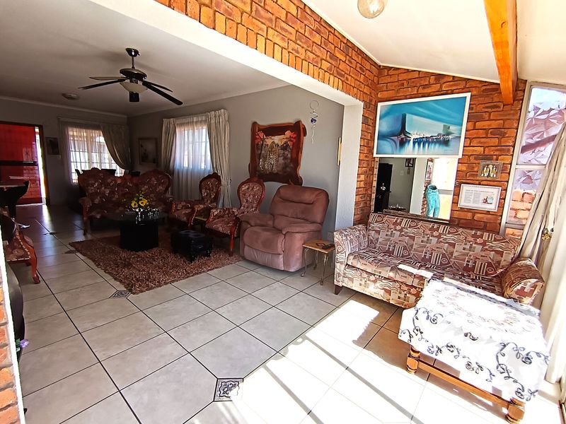 Spacious living area featuring exposed brick walls, tiled flooring, and a ceiling fan, providing a comfortable and character-filled space.