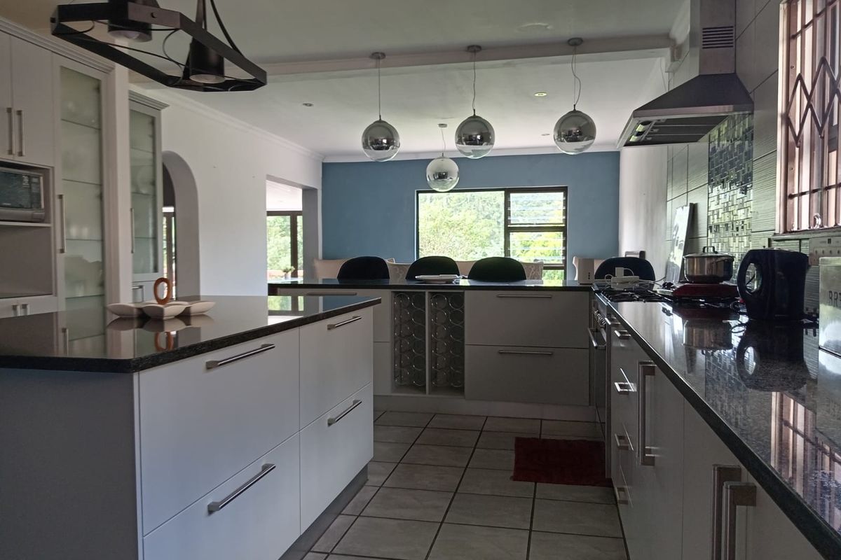 Modern kitchen featuring a central island, granite countertops, built-in gas hob with extractor, and integrated wine storage, flowing into an open-plan living area.