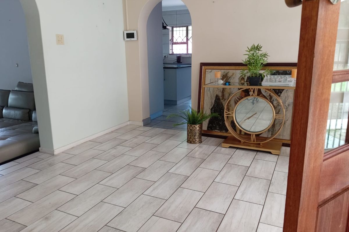 A living area featuring light-toned tiled flooring and distinctive arched doorways leading to adjacent rooms, providing a neutral foundation for interior design.
