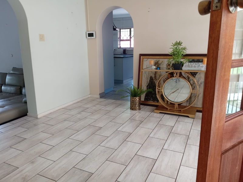 A living area featuring light-toned tiled flooring and distinctive arched doorways leading to adjacent rooms, providing a neutral foundation for interior design.