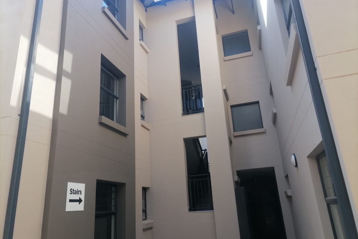An exterior view of an apartment building complex featuring a central stairwell, modern facade finishes, and integrated balustrades.