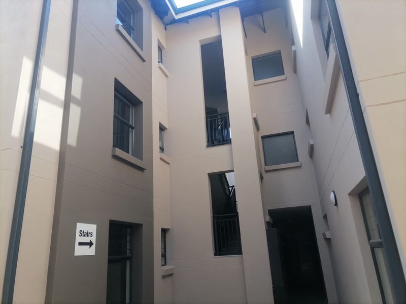 An exterior view of an apartment building complex featuring a central stairwell, modern facade finishes, and integrated balustrades.