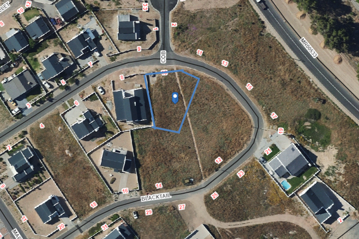 An aerial view of a vacant residential plot situated within a developed suburban estate, ready for new construction.