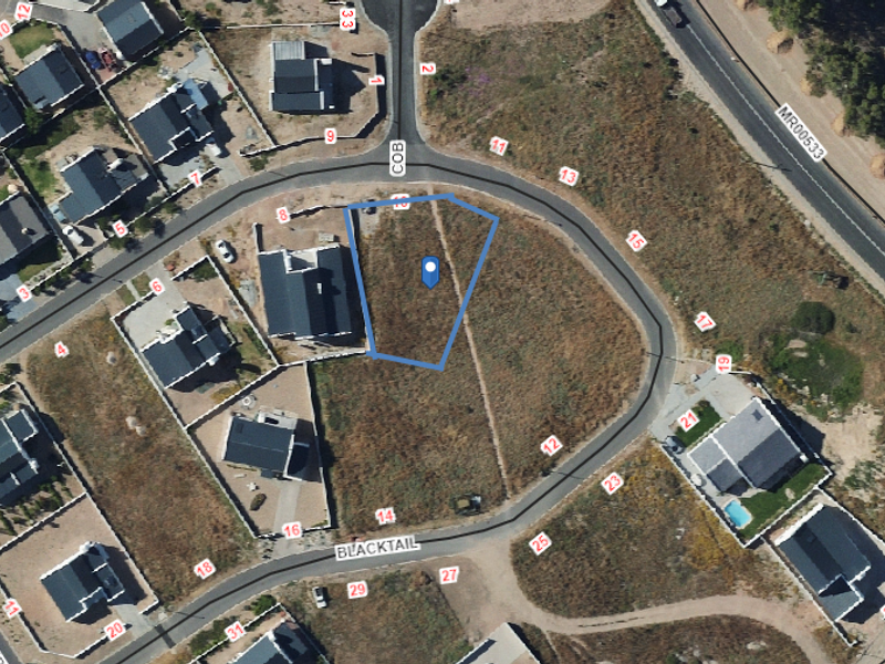An aerial view of a vacant residential plot situated within a developed suburban estate, ready for new construction.