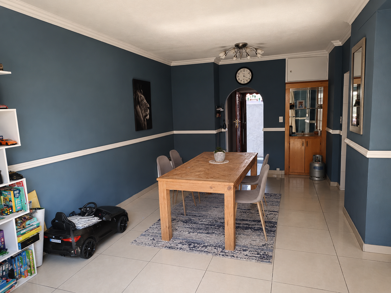 A dining room featuring blue walls with chair rail and crown molding, tiled flooring, and a built-in wooden cabinet.