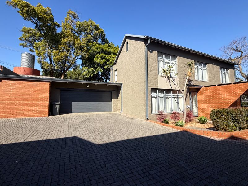 Front exterior view of a townhouse featuring a paved driveway, integrated garage, and a combination of brick and painted masonry finishes.