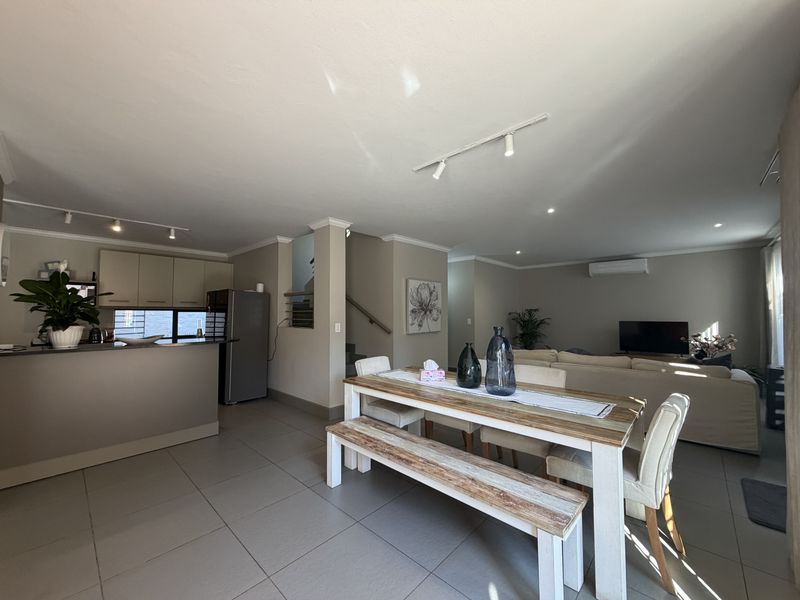 Spacious open-plan living area featuring a modern kitchen with island, tiled flooring, and integrated air conditioning, seamlessly connecting to the dining and lounge space.
