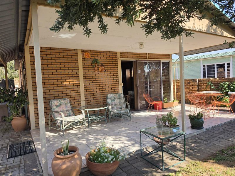 A covered outdoor patio area featuring brick wall finishes and tiled flooring, providing a functional space for outdoor relaxation and entertaining.