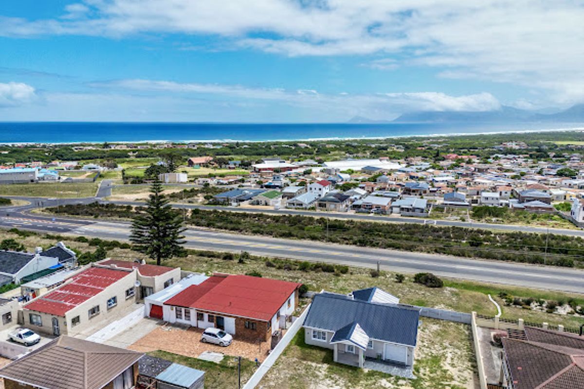 Aerial view of the property showing the roof structure, driveway, and surrounding coastal neighborhood with ocean views.