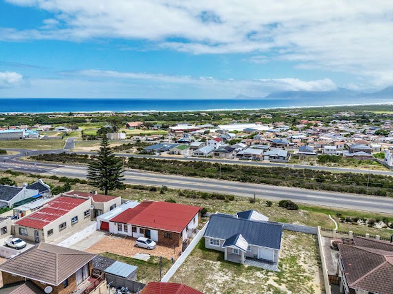 Aerial view of the property showing the roof structure, driveway, and surrounding coastal neighborhood with ocean views.