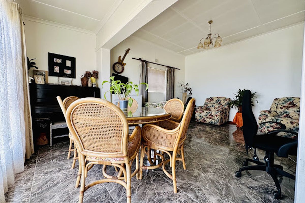 A spacious living area featuring polished marble-look floor tiles and a central ceiling light fixture, offering a versatile layout for dining or relaxation.