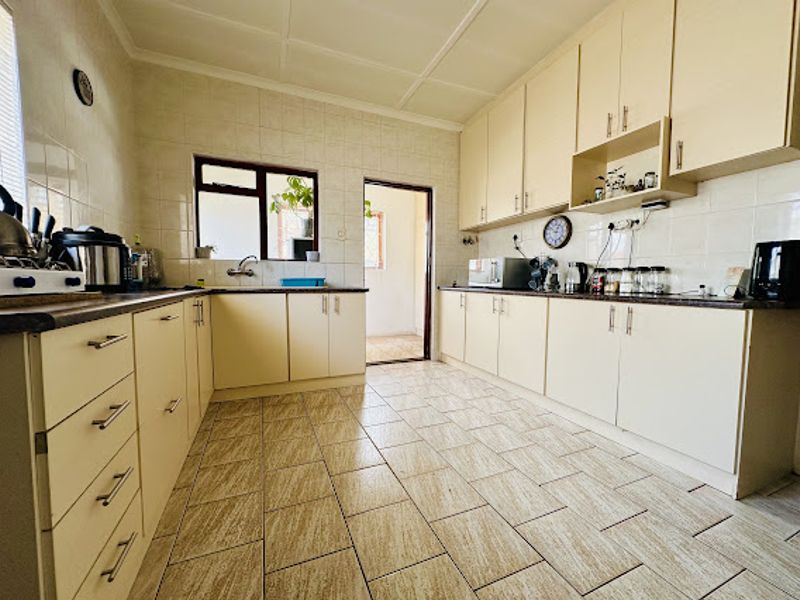 A functional kitchen featuring extensive built-in cabinetry, tiled flooring, and a tiled backsplash, offering ample storage and workspace for daily meal preparation.