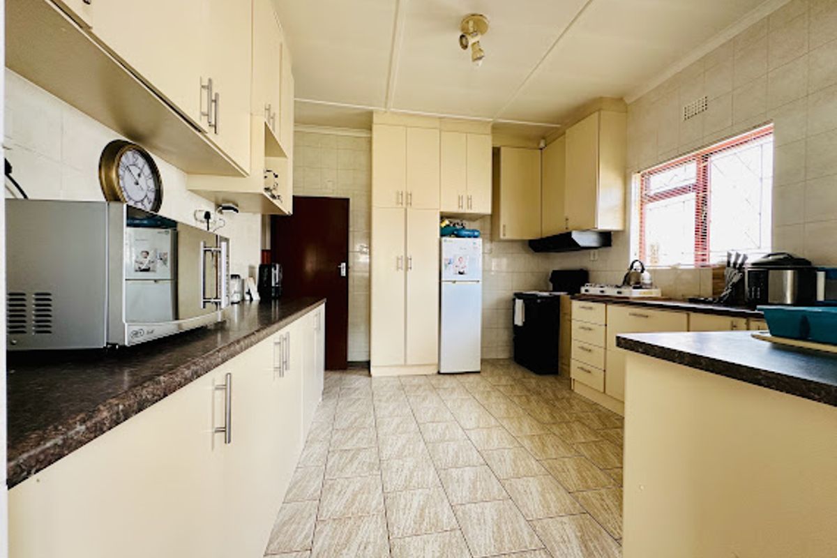A functional kitchen featuring ample built-in cabinetry, laminate countertops, tiled flooring, and a tiled backsplash, offering a practical layout for daily meal preparation.
