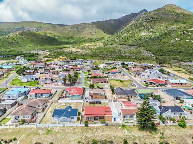 An aerial view of a residential neighborhood situated at the base of a mountain range, showcasing the surrounding properties and local infrastructure.