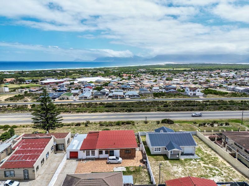 Aerial view of the property showing the roof structure, paved driveway, and surrounding residential neighbourhood with coastal and mountain views.
