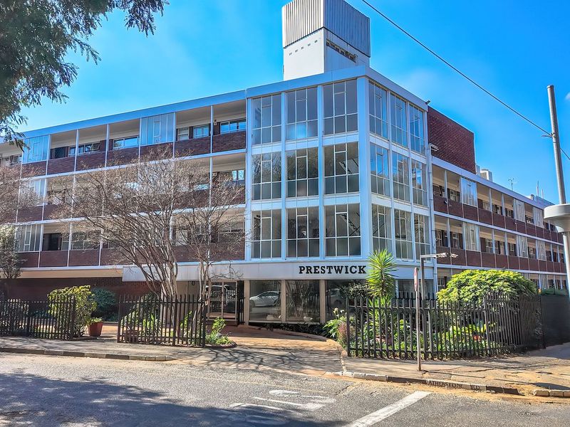 Street-level view of the Prestwick apartment building, featuring a multi-story facade with large glass windows and brick exterior finishes.