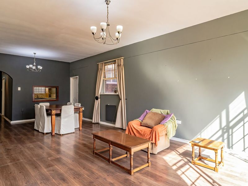 Spacious open-plan living and dining area featuring laminate flooring, arched entryway, and dual chandeliers, offering a versatile layout for modern living.