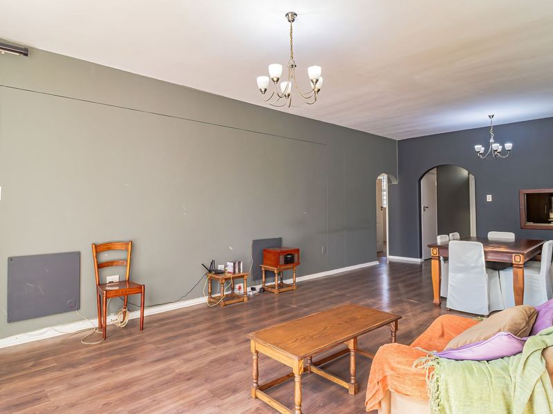 Spacious open-plan living and dining area featuring laminate flooring, an arched entryway, and a convenient pass-through window connecting to the kitchen.
