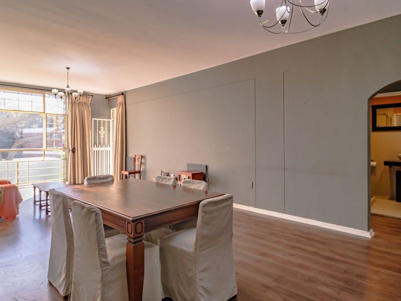 Spacious open-plan living and dining area featuring laminate flooring, large windows for natural light, and an arched doorway leading to an adjacent room.