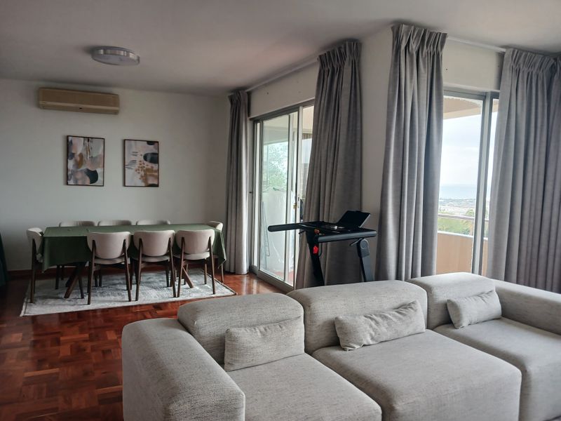 Spacious open-plan living and dining area featuring warm parquet flooring, large sliding glass doors, and integrated air conditioning.