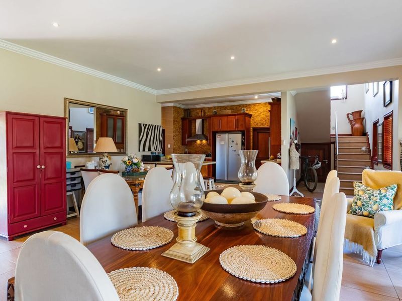 Spacious open-plan dining and kitchen area featuring tiled floors, recessed lighting, crown molding, and a functional kitchen layout with wooden cabinetry.