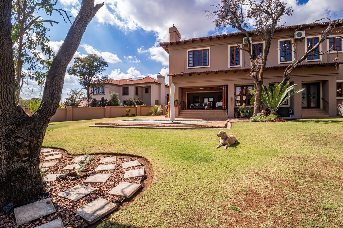 Rear view of a two-story house featuring a landscaped garden, a swimming pool, and a covered patio area.