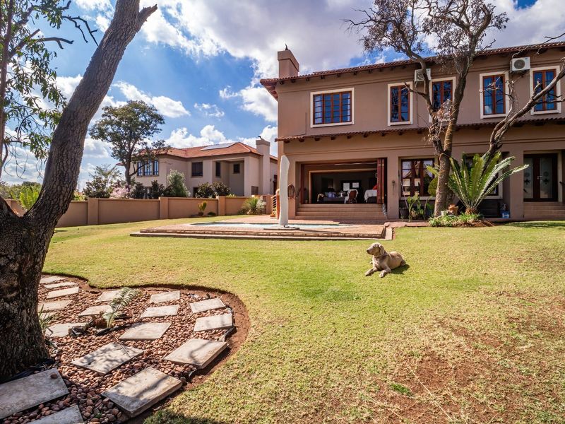 Rear view of a two-story house featuring a landscaped garden, a swimming pool, and a covered patio area.