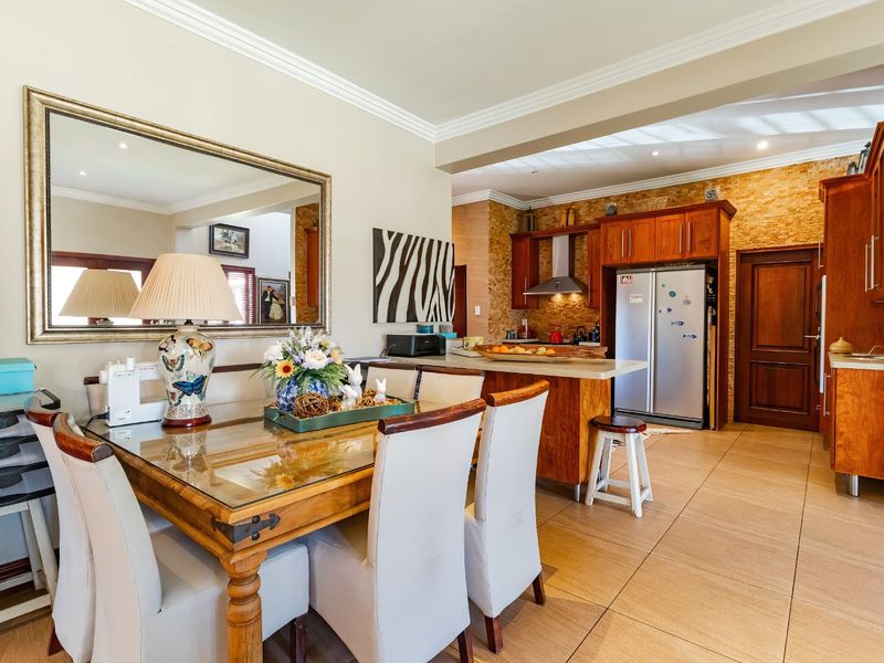 Open plan kitchen and dining area featuring warm wood cabinetry, stone tile flooring, and a textured stone feature wall with integrated lighting.