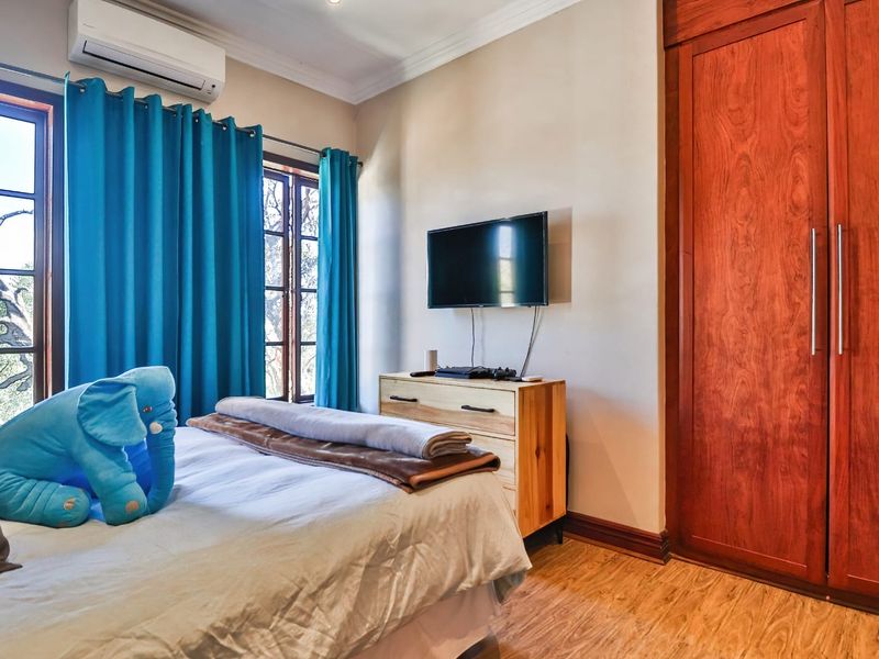 A well-maintained bedroom featuring timber-look flooring, a built-in wardrobe, and a wall-mounted air conditioning unit.