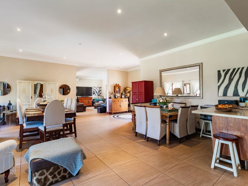 Spacious open-plan living and dining area featuring tiled flooring, recessed downlighting, and a functional kitchen island, creating a versatile and connected living space.
