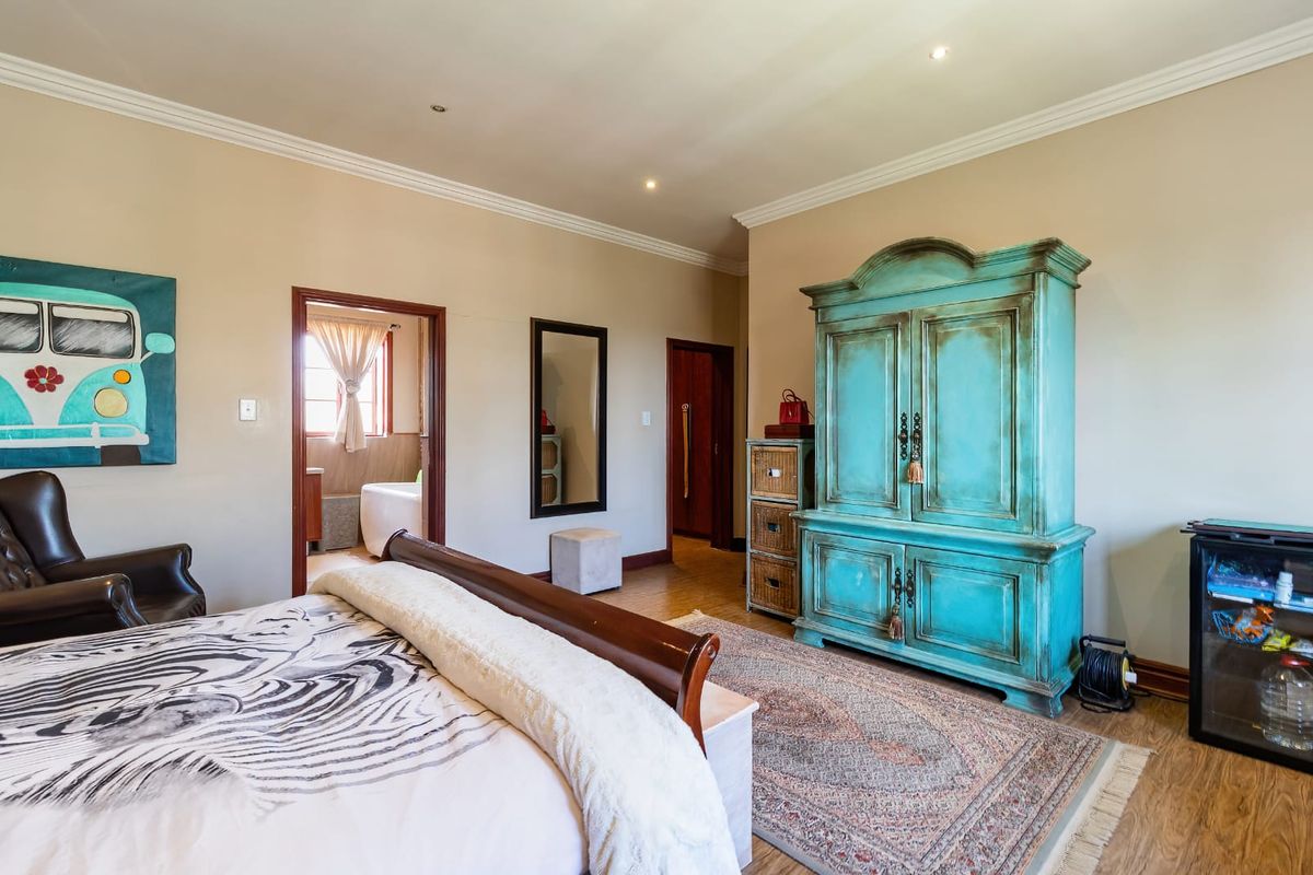 Spacious bedroom featuring laminate flooring, crown molding, and recessed lighting, with an adjoining en-suite bathroom visible through the doorway.