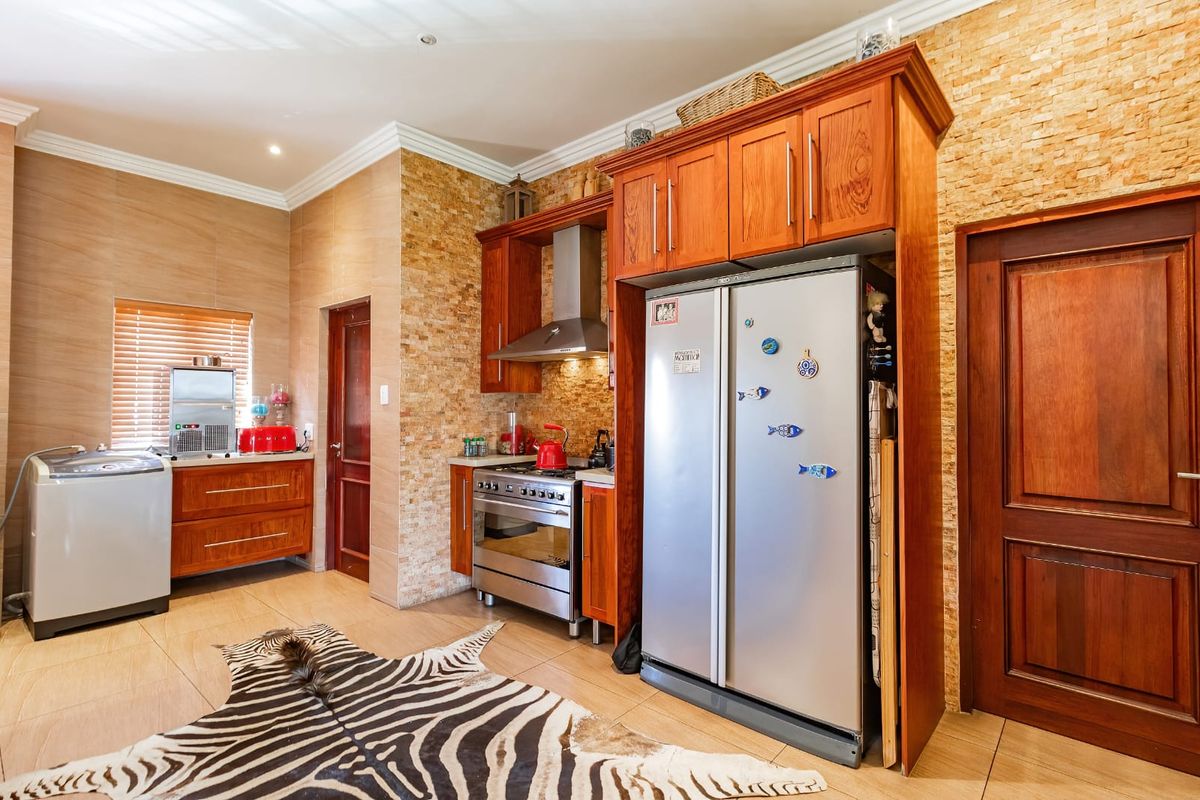 A well-appointed kitchen featuring warm wooden cabinetry, stone tile backsplash, stainless steel appliances, and tiled flooring with recessed lighting.