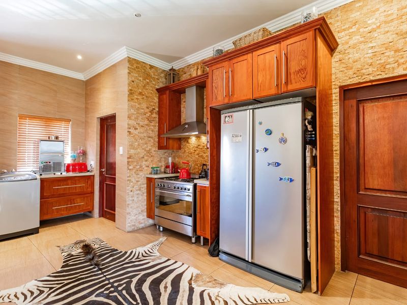A well-appointed kitchen featuring warm wooden cabinetry, stone tile backsplash, stainless steel appliances, and tiled flooring with recessed lighting.