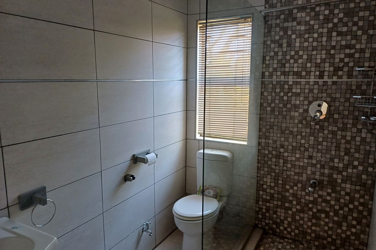 Modern bathroom featuring a walk-in shower with a mosaic tile accent wall, neutral ceramic wall tiles, and a clean, functional layout.